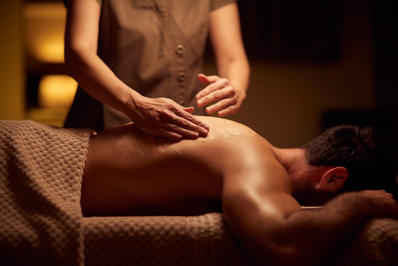 Spa therapist giving a man a relaxing back massage treatment.
